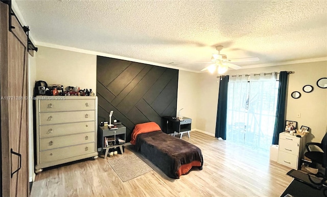 bedroom with crown molding, light hardwood / wood-style floors, a textured ceiling, a barn door, and ceiling fan