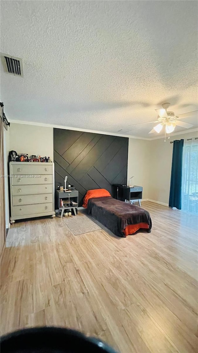 bedroom featuring light hardwood / wood-style floors, ceiling fan, ornamental molding, and wooden walls