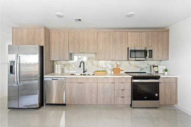 kitchen featuring decorative backsplash, stainless steel appliances, sink, light brown cabinets, and light tile patterned flooring