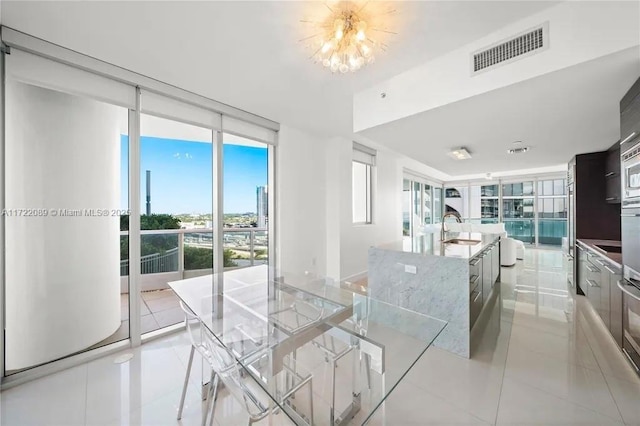 kitchen featuring floor to ceiling windows, sink, light tile patterned floors, and a large island with sink