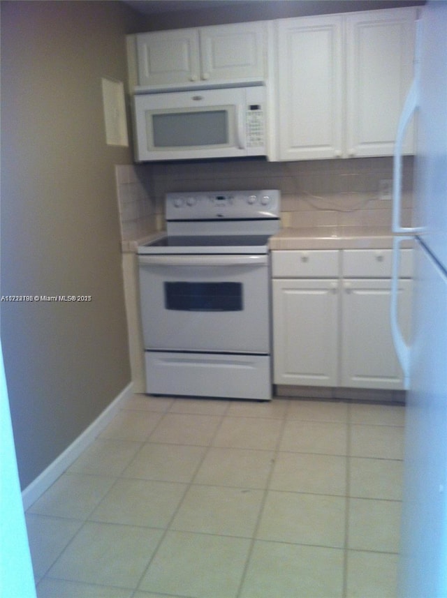 kitchen featuring white cabinetry, light tile patterned flooring, and white appliances