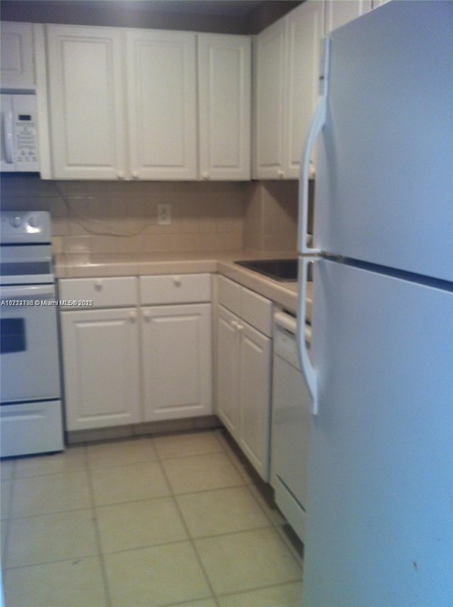 kitchen featuring white cabinets, light tile patterned flooring, white appliances, and sink