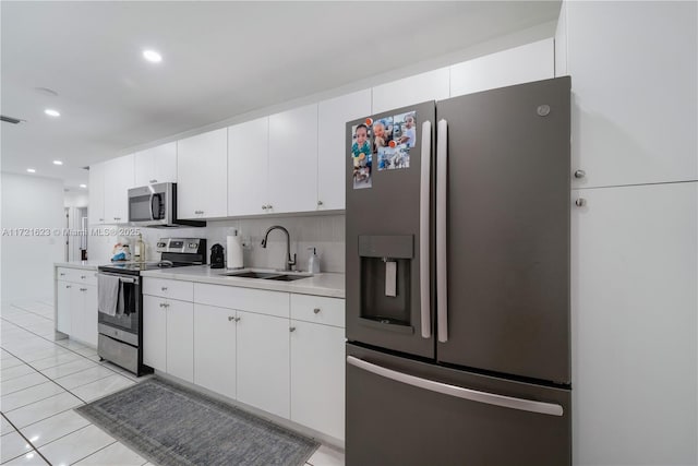 kitchen featuring white cabinets, appliances with stainless steel finishes, light tile patterned flooring, and sink