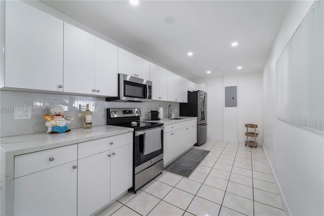 kitchen with appliances with stainless steel finishes, tasteful backsplash, light stone counters, sink, and white cabinetry