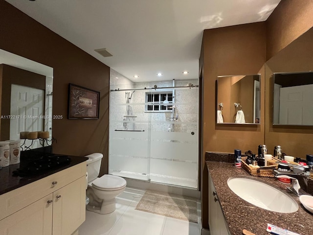 bathroom with tile patterned floors, toilet, vanity, and walk in shower