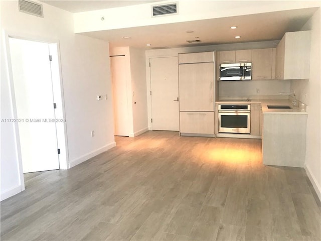 kitchen featuring light brown cabinetry, stainless steel appliances, light hardwood / wood-style flooring, and sink