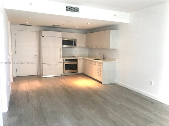 kitchen with hardwood / wood-style floors, appliances with stainless steel finishes, and sink