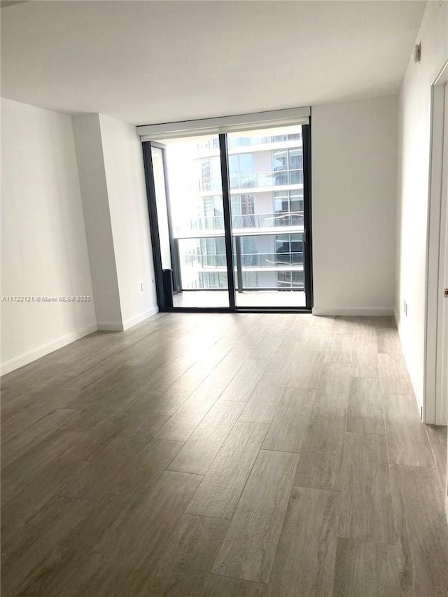 spare room with hardwood / wood-style floors, a wall of windows, and a wealth of natural light