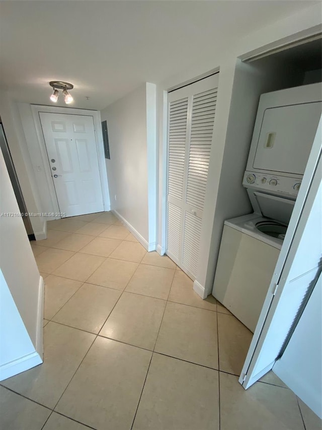 laundry room with light tile patterned floors and stacked washer / dryer