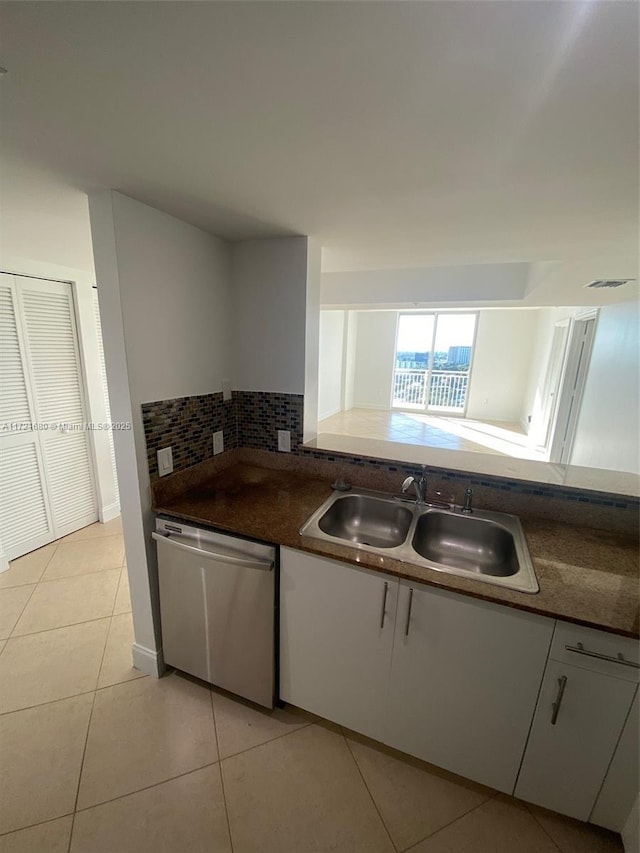 kitchen with sink, stainless steel dishwasher, light tile patterned floors, tasteful backsplash, and white cabinetry