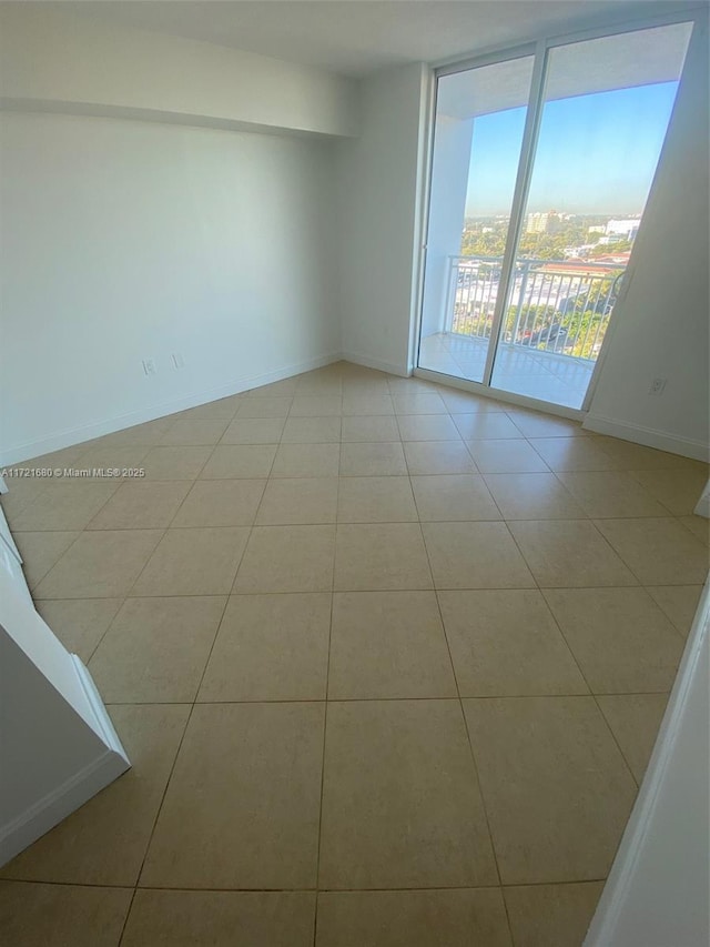 tiled empty room featuring a wall of windows