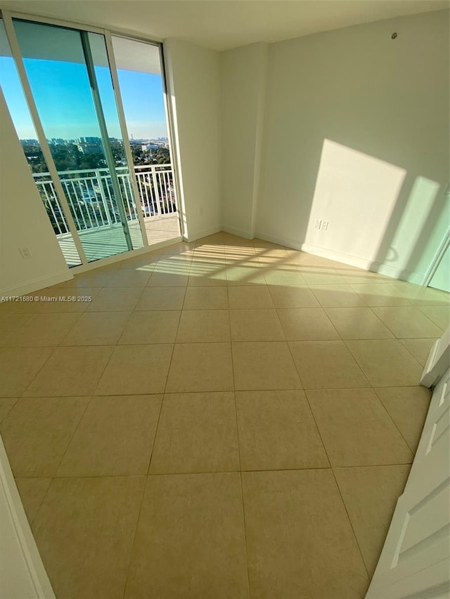 spare room featuring a wall of windows and light tile patterned floors