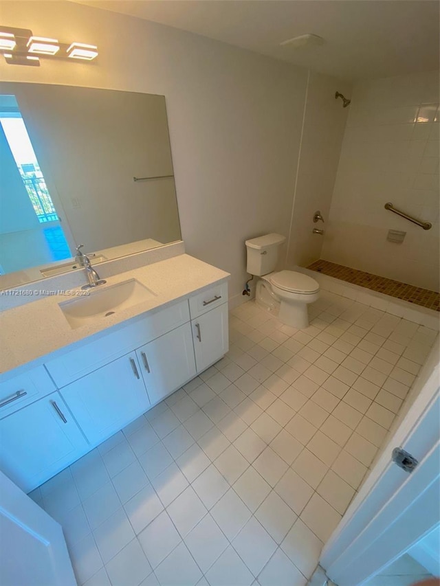 bathroom with toilet, a tile shower, vanity, and tile patterned floors