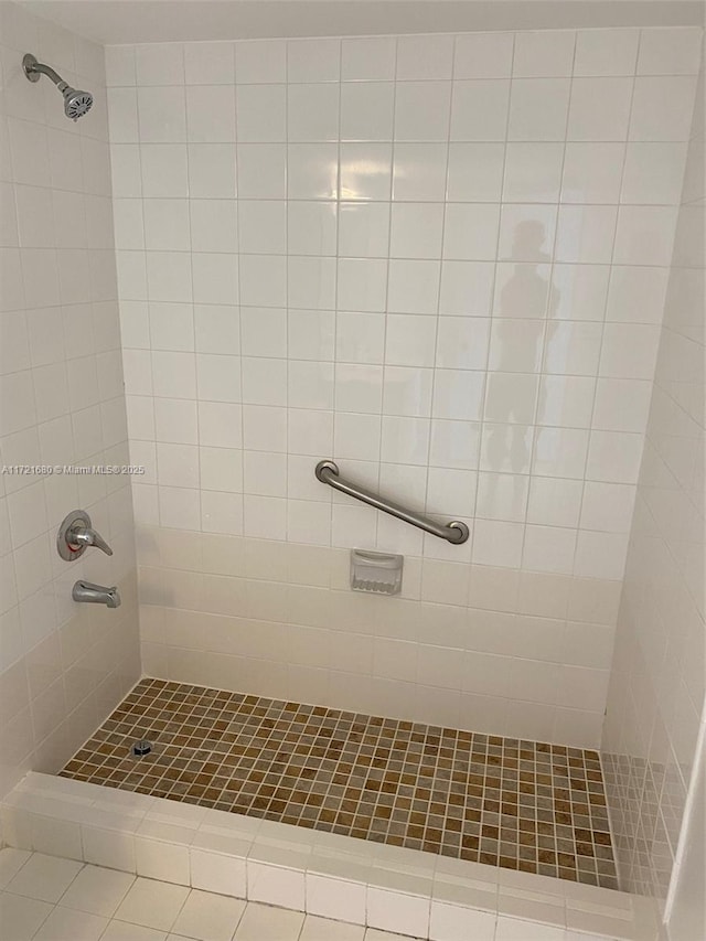 bathroom with a tile shower and tile patterned floors