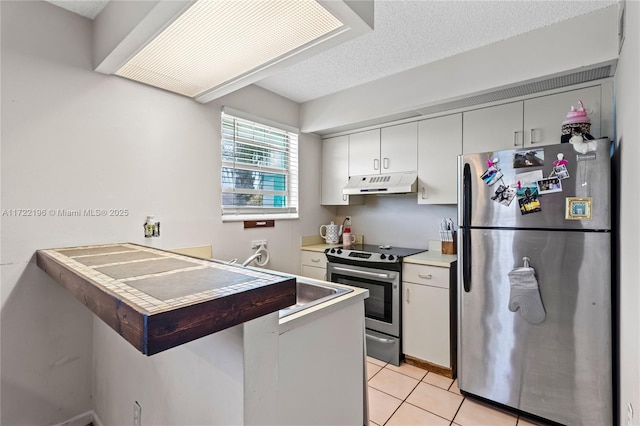 kitchen with kitchen peninsula, appliances with stainless steel finishes, a textured ceiling, sink, and light tile patterned floors