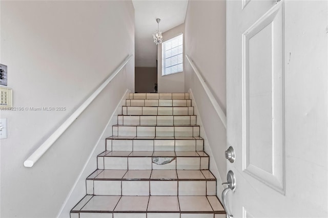 staircase with tile patterned floors and an inviting chandelier