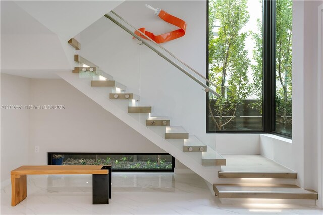 stairway with plenty of natural light and a glass covered fireplace