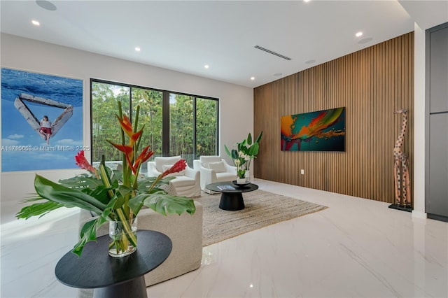 living area with wood walls, visible vents, marble finish floor, and recessed lighting