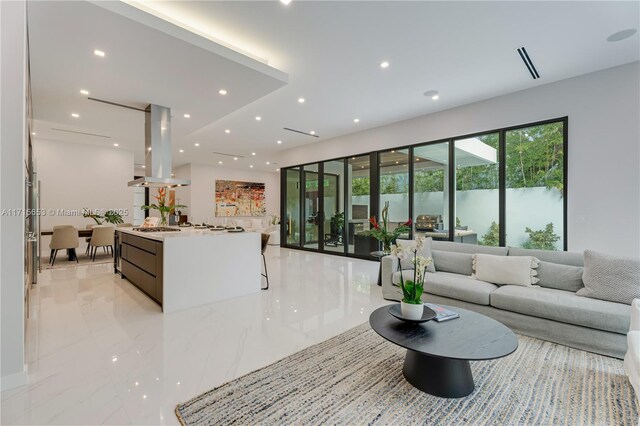 kitchen featuring island exhaust hood, a sink, appliances with stainless steel finishes, modern cabinets, and a kitchen bar