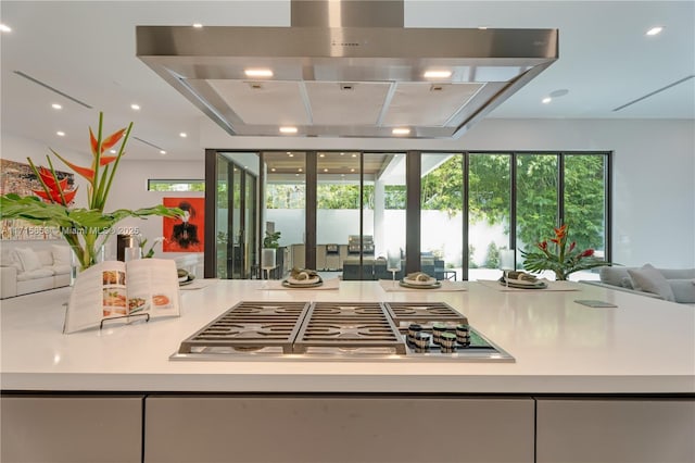 kitchen featuring stainless steel gas cooktop, island exhaust hood, recessed lighting, light countertops, and open floor plan