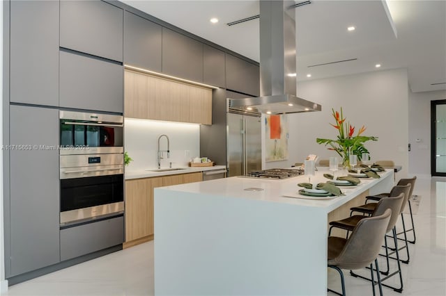 kitchen featuring modern cabinets, appliances with stainless steel finishes, a breakfast bar area, island exhaust hood, and a sink