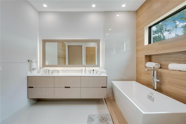 bathroom featuring recessed lighting, a freestanding bath, a sink, and double vanity