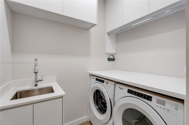 laundry room with cabinet space, a sink, and washing machine and clothes dryer