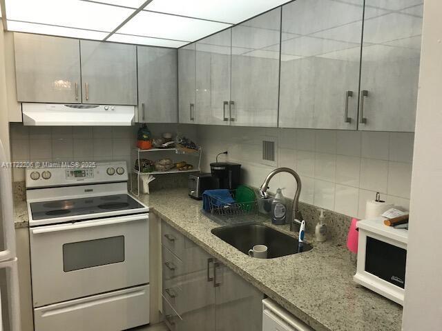 kitchen featuring sink, tasteful backsplash, electric range oven, and light stone countertops