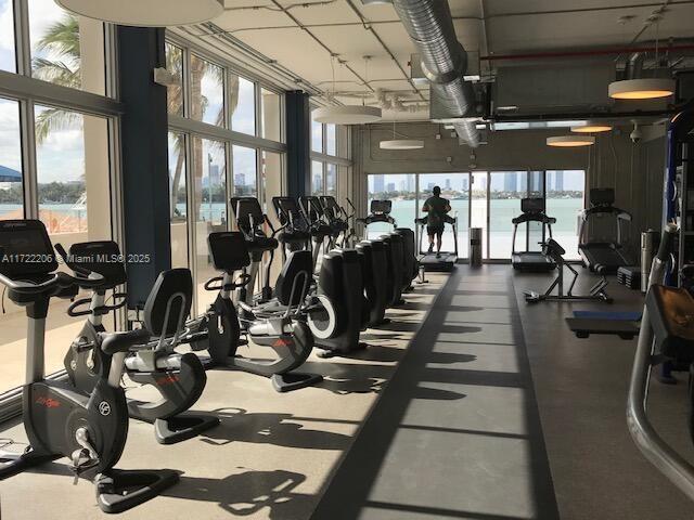 exercise room with a high ceiling, expansive windows, and a water view