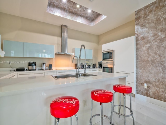 kitchen featuring wall chimney range hood, white cabinetry, light countertops, and oven