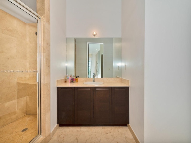 full bath featuring marble finish floor, vanity, baseboards, and a stall shower