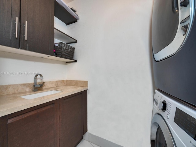 clothes washing area featuring stacked washing maching and dryer, a sink, and cabinet space