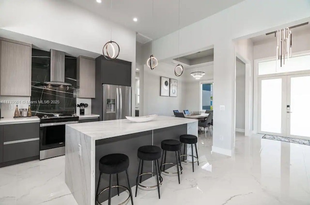 kitchen featuring a breakfast bar, wall chimney exhaust hood, a kitchen island, and appliances with stainless steel finishes