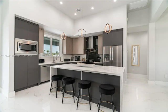 kitchen with a center island, sink, wall chimney exhaust hood, appliances with stainless steel finishes, and a breakfast bar area