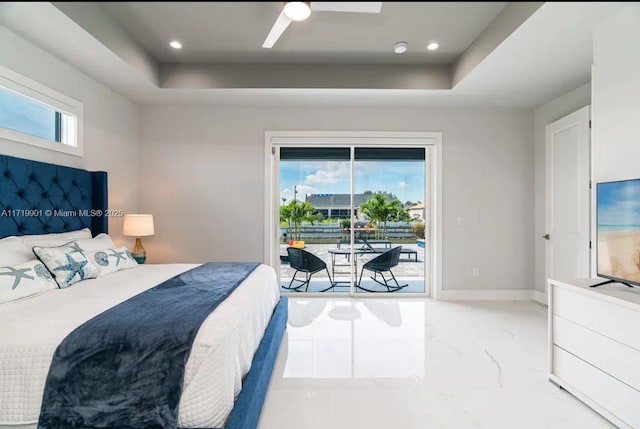 bedroom featuring multiple windows, access to outside, a raised ceiling, and ceiling fan