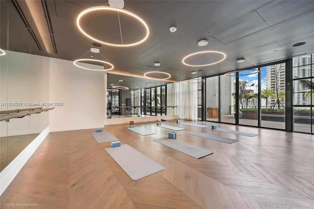 workout area featuring a wall of windows and parquet flooring