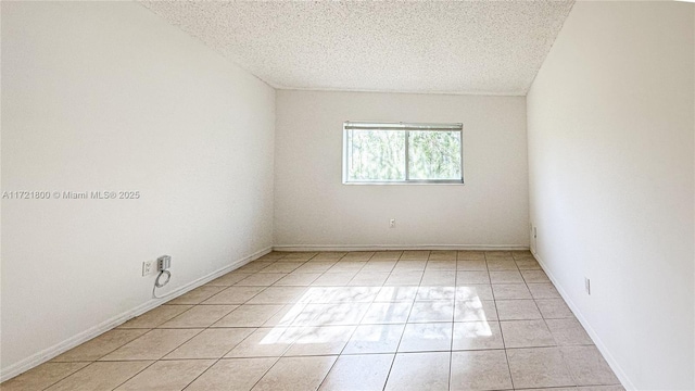 tiled empty room featuring a textured ceiling