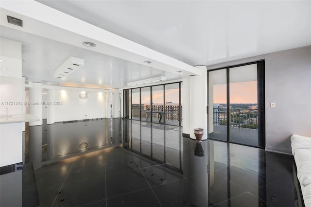 tiled empty room featuring floor to ceiling windows, plenty of natural light, and a wall mounted air conditioner