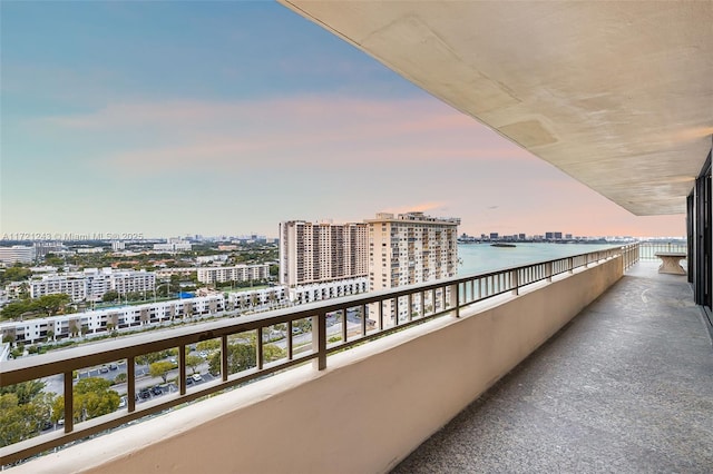 balcony at dusk featuring a water view