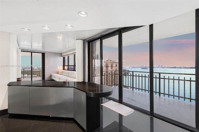 unfurnished bedroom with dark tile patterned flooring, floor to ceiling windows, and a water view