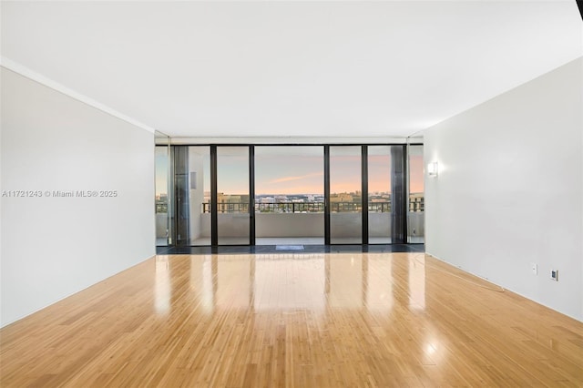 unfurnished room with floor to ceiling windows and hardwood / wood-style flooring