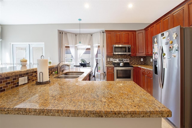 kitchen with pendant lighting, backsplash, sink, light stone countertops, and appliances with stainless steel finishes