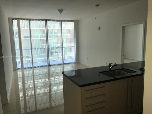 kitchen featuring light tile patterned flooring, a wall of windows, and sink