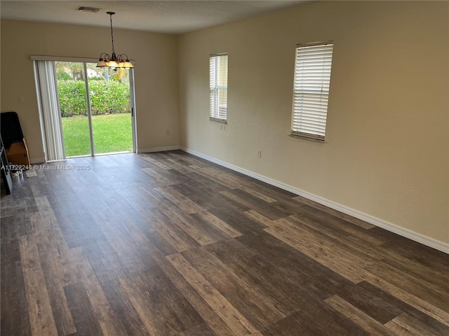 spare room featuring dark hardwood / wood-style floors and an inviting chandelier