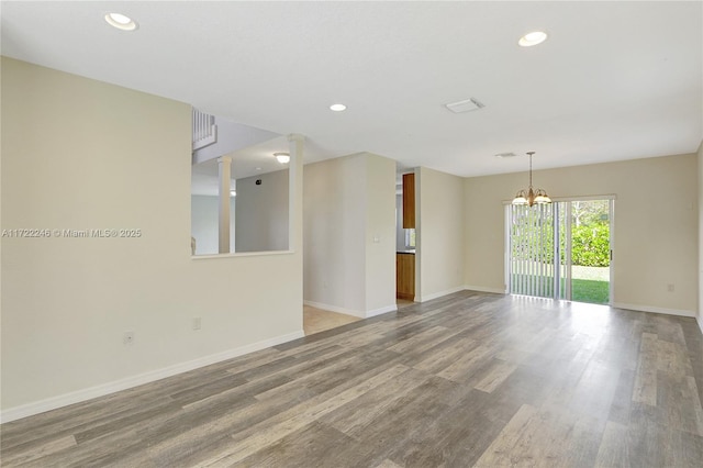 empty room with wood-type flooring and a chandelier