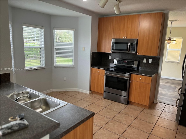 kitchen featuring appliances with stainless steel finishes, ceiling fan with notable chandelier, sink, light tile patterned floors, and pendant lighting