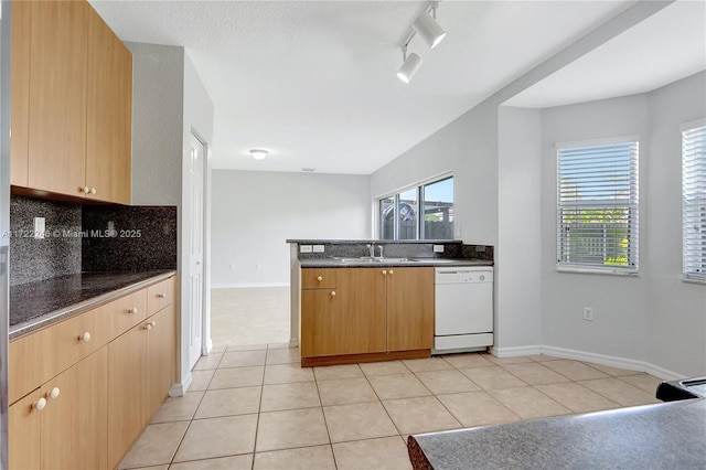 kitchen with sink, light tile patterned floors, rail lighting, white dishwasher, and tasteful backsplash