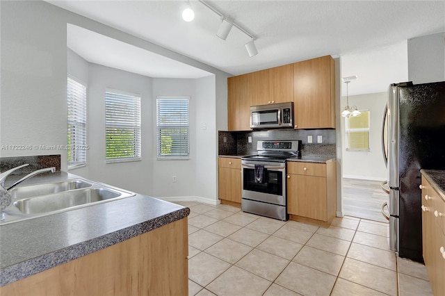 kitchen featuring appliances with stainless steel finishes, pendant lighting, sink, backsplash, and light tile patterned floors