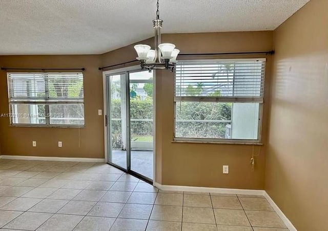 doorway to outside featuring light tile patterned flooring, a chandelier, and a textured ceiling