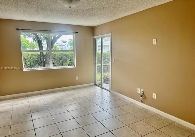 spare room featuring light tile patterned floors and a textured ceiling